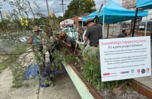 Volunteers remove plants from metal planting containers outside Cocoa Cinnamon.